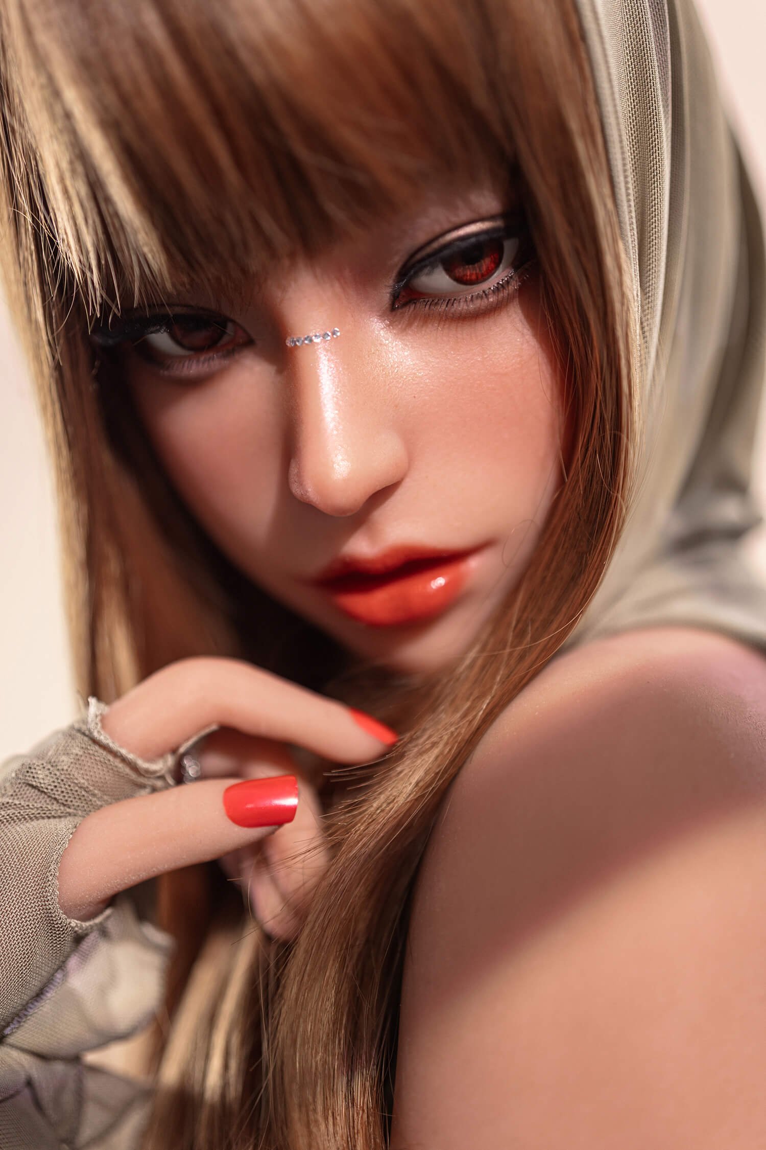 Close-up of a woman's face with red contact lenses, smoky eye makeup, a beige hood, and coral nails resting near her chin.