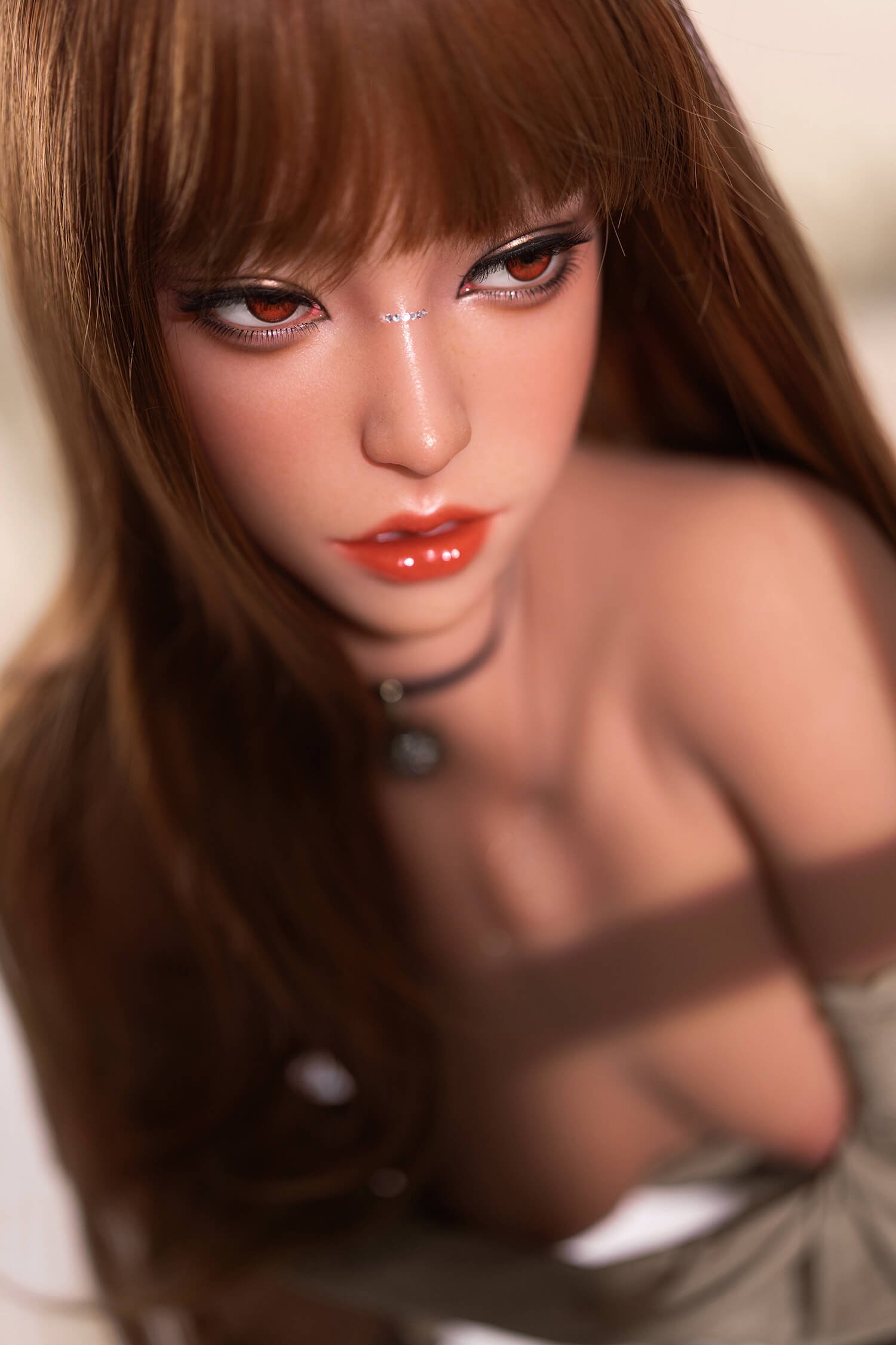 Close-up of a doll's face with long brown hair, bold eye makeup, and glossy red lips on a light background.