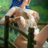Fantasy elf woman with long blue hair, pointed ears, and a jeweled headpiece leaning on a wooden railing outdoors.