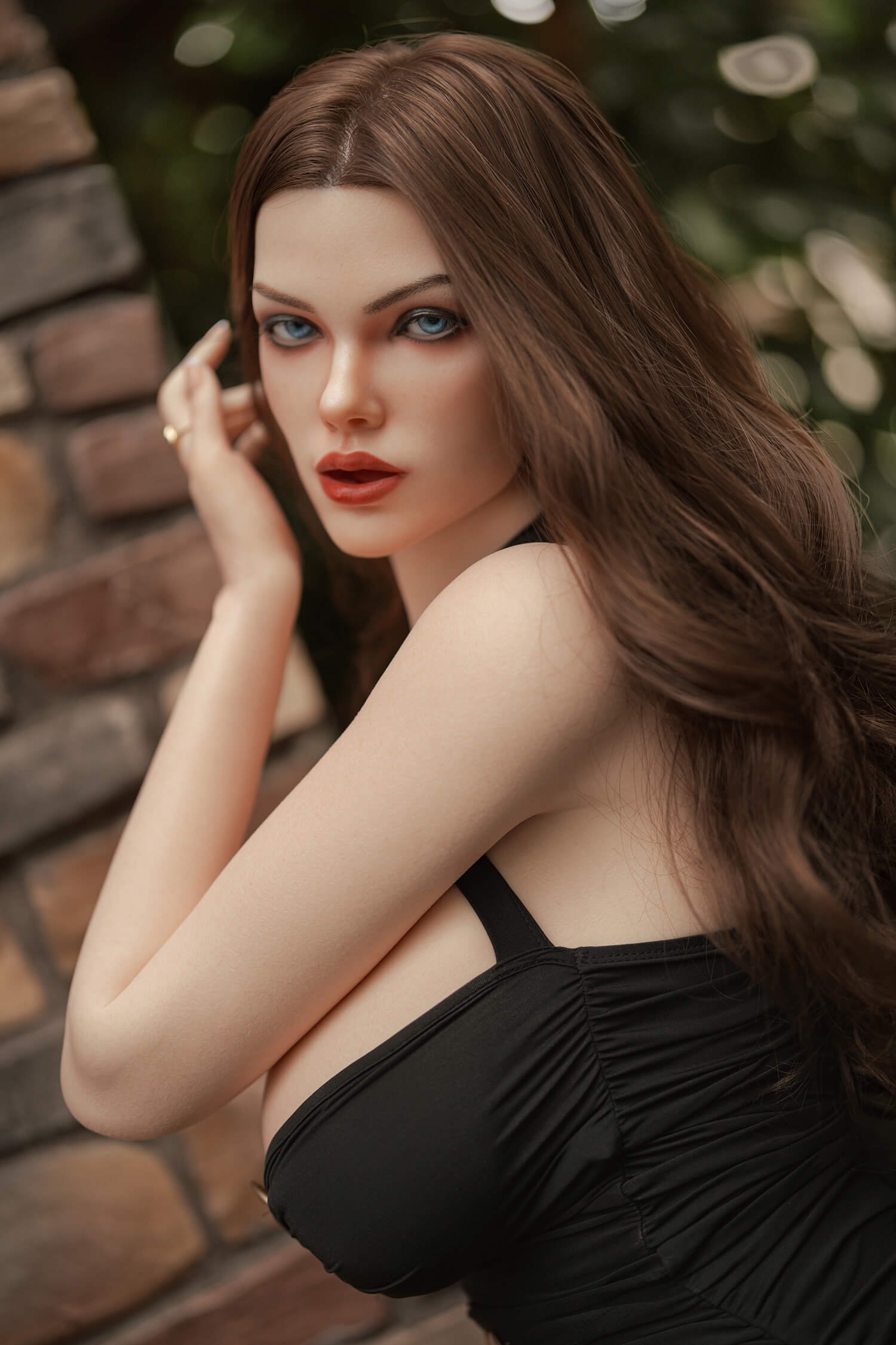 Close-up of a woman with blue eyes and long brown hair wearing a black top outdoors, looking at the camera with a soft expression.