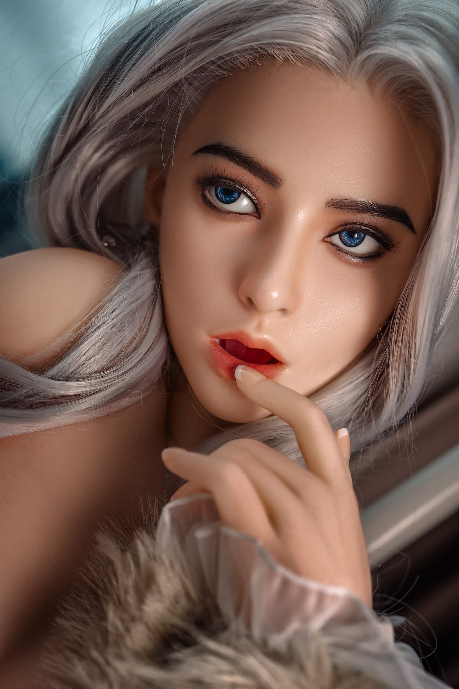 Close-up portrait of a woman with striking blue eyes and silver hair, soft makeup, and a finger resting near her lips.
