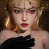Close-up of a fashion doll with blonde hair and blue eyes, wearing a gold star-spangled headpiece and a black feathered outfit.