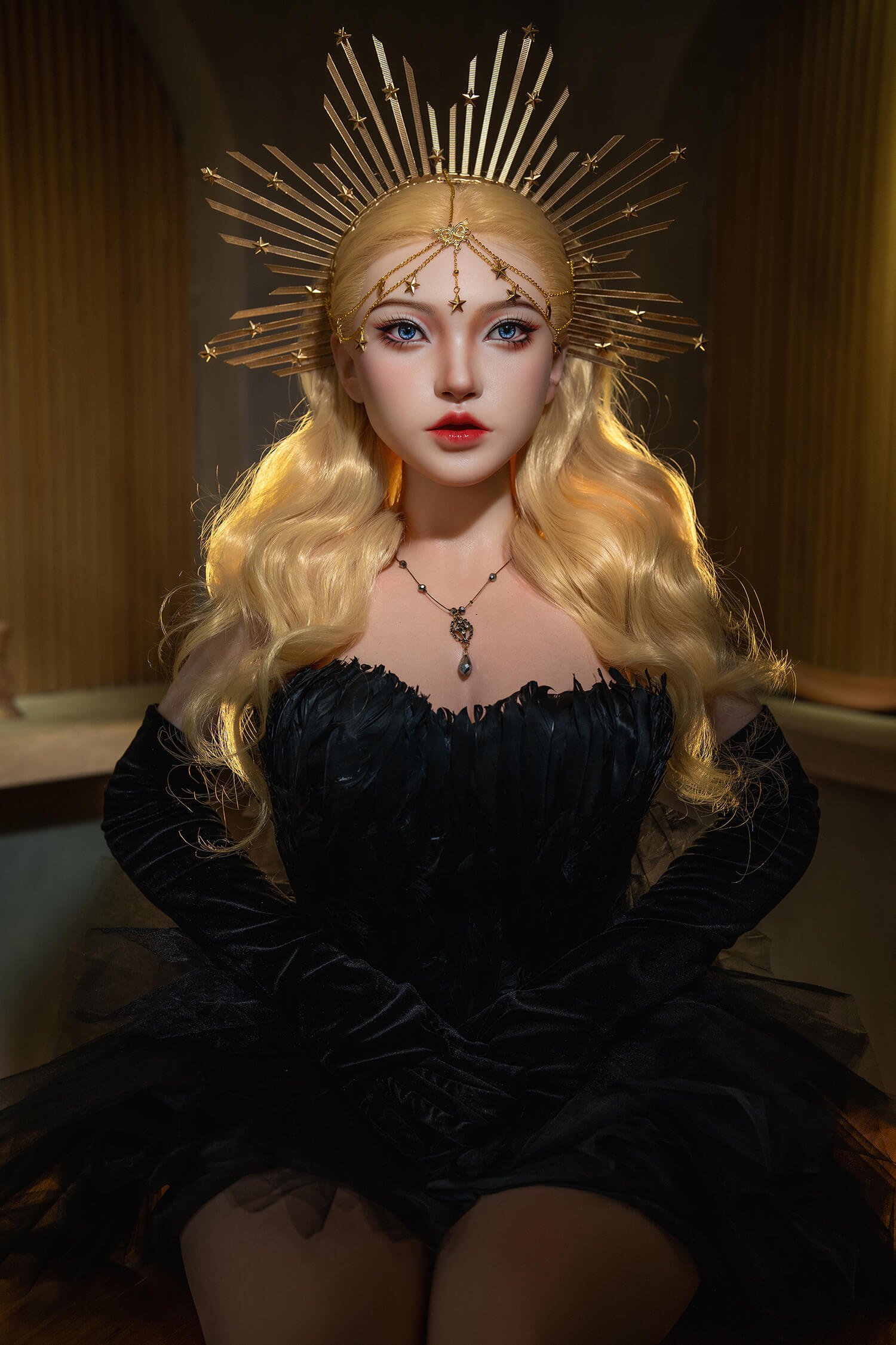 Doll-like figure with long blonde hair, wearing a gold sunburst crown, blue eyes, red lips, and a black off-the-shoulder dress with a necklace.