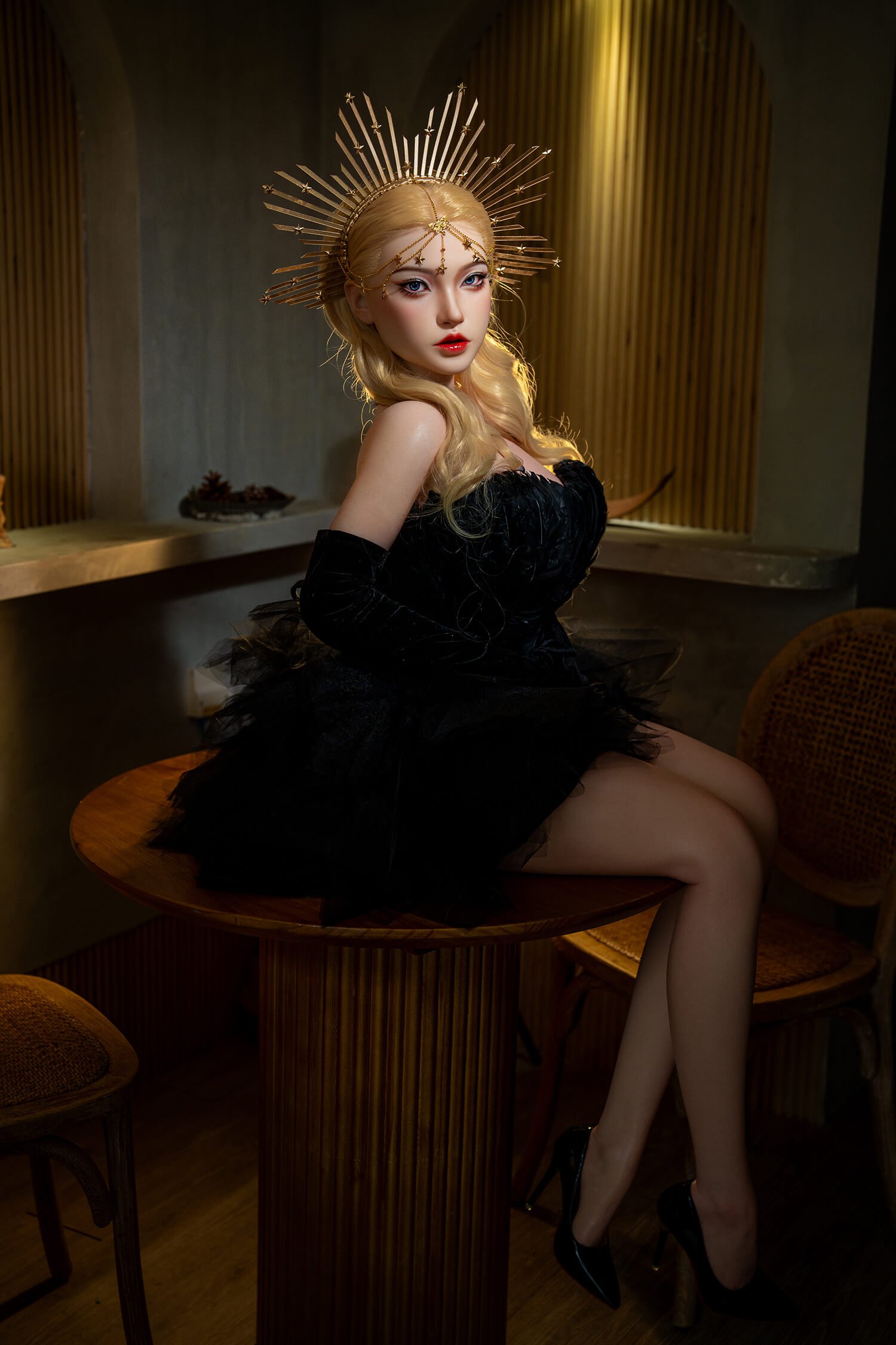 Woman wearing a gold sunburst crown and black dress, seated on a round wooden table in a warm, dim room.
