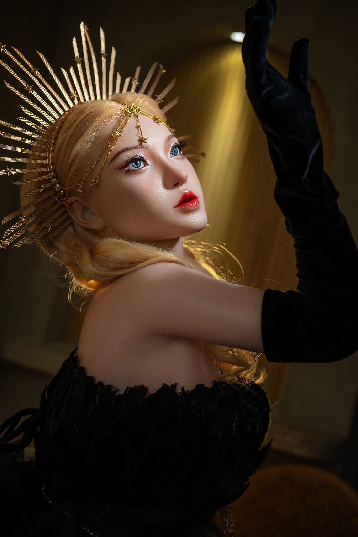 Portrait of a blonde woman wearing a gold sunburst crown, dramatic makeup, and a black velvet sleeve, looking upward.