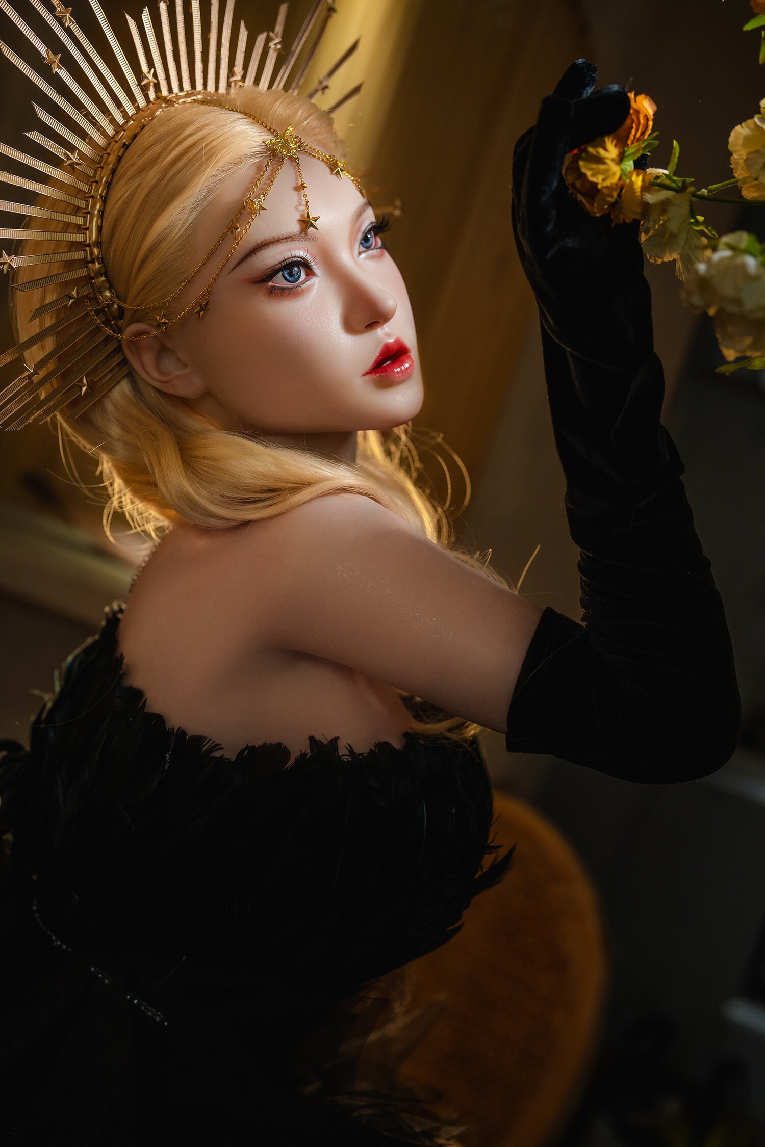Close-up portrait of a woman with blonde hair wearing a gold sunburst headpiece and black velvet gloves, reaching toward yellow flowers.