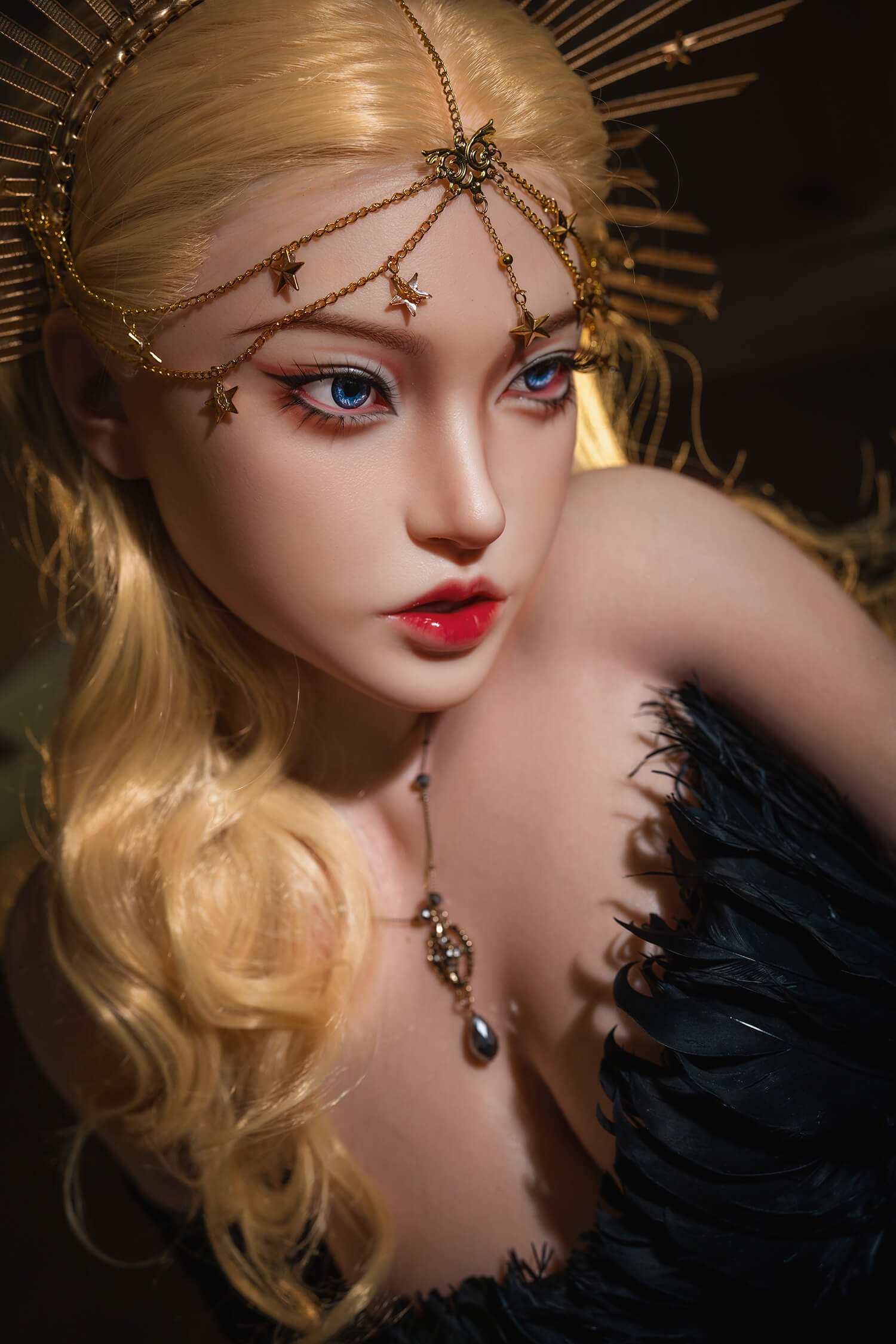 Close-up portrait of a person with golden hair wearing a gold chain headpiece with star charms and a black feathered outfit, looking to the side.