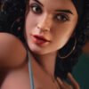 Close-up of a woman with dark curly hair, a black headband, and large hoop earrings, gazing softly to the side.
