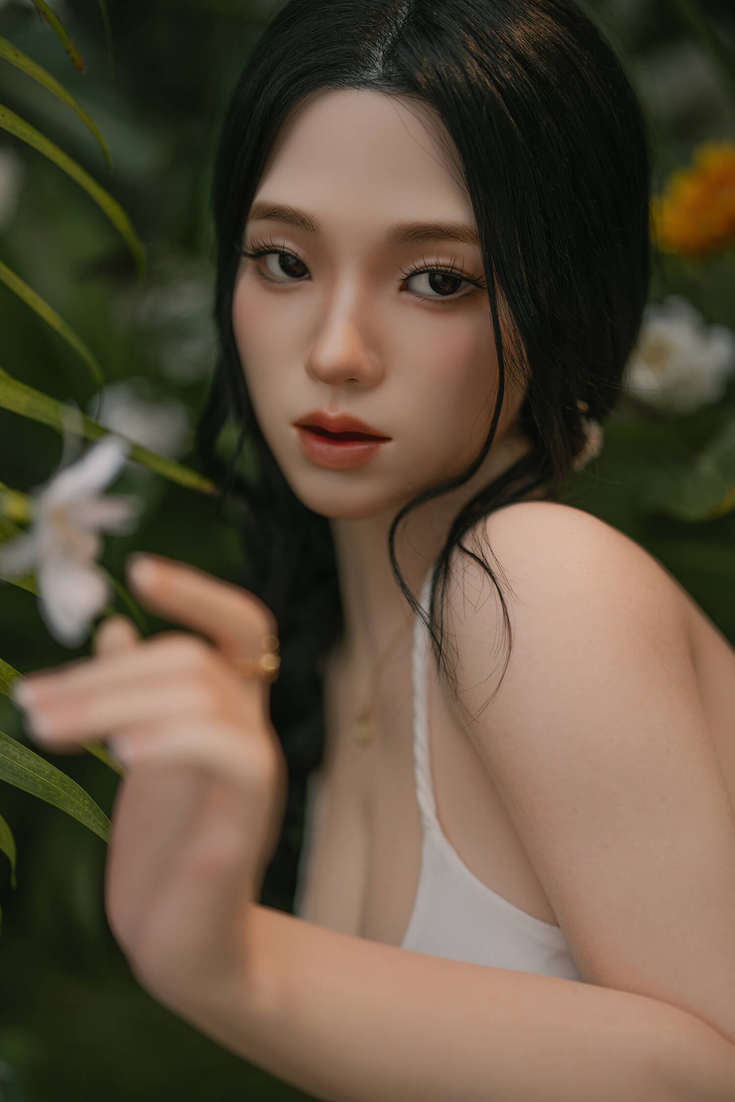 Close-up portrait of a woman with dark hair and red lips among lush green foliage, looking at the camera.