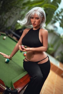 Platinum-haired woman in a black sleeveless top leans over a billiards table, holding a red ball in her hand.