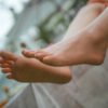 Close-up of bare feet resting on a ledge outdoors, with a soft, blurred background behind them.